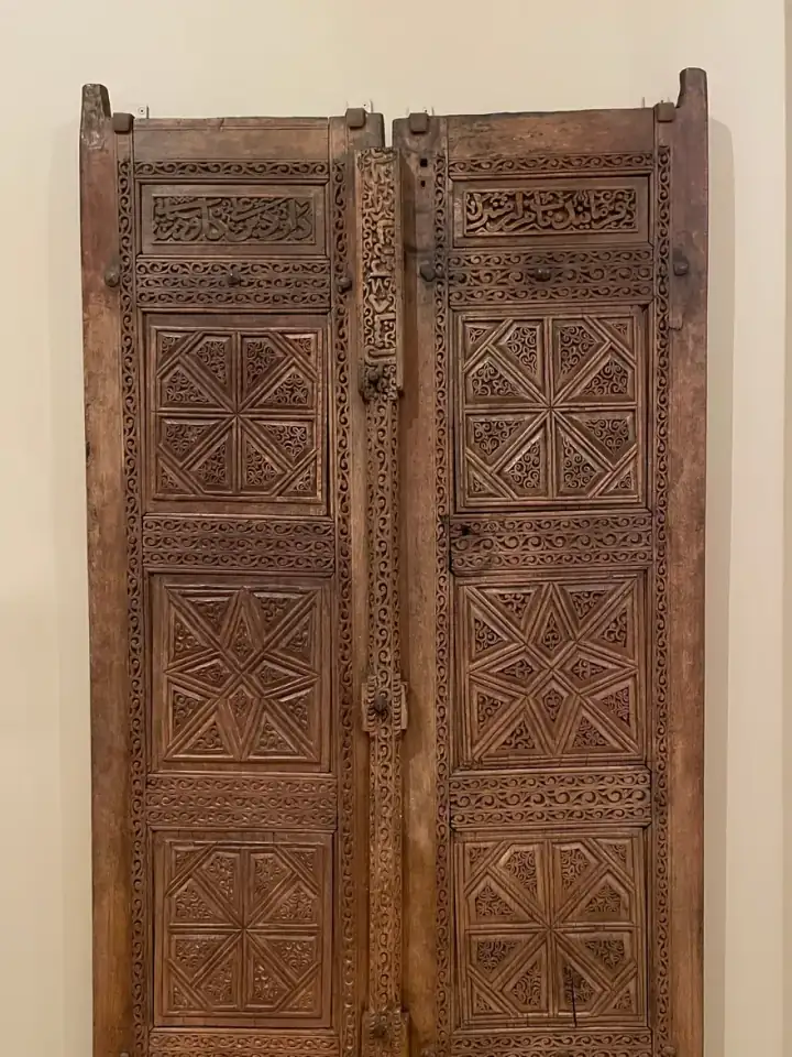 Çift kanatlı oyma ahşap kapı; panolarında yıldız göbekli geometrik kuruluş.